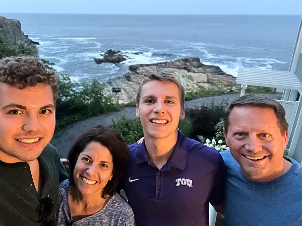 Craig and his family smiling on a coastal overlook